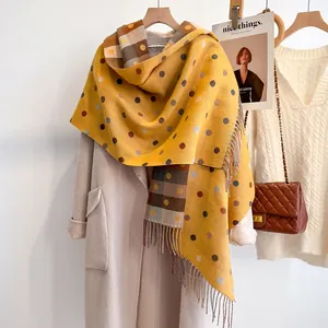 Detail of ginger scarf with polka dots and plaid patterns on light coat with fringe