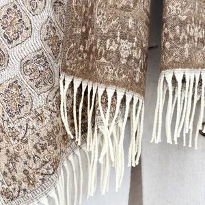 Detail of ethnic jacquard pattern and long beige tassels on a warm brown winter scarf