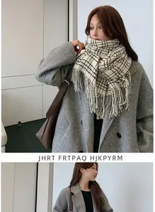 Close-up of black and white plaid scarf with tassels styled on a grey wool coat