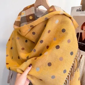 Detail of yellow polka dot cashmere-like scarf showing soft texture and fringe edges