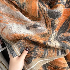 Vue détaillée de l'écharpe à motif marbré orange et marron avec des détails de franges