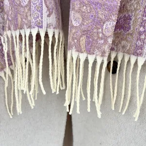 Detail of paisley pattern on violet and gold cashmere shawl with elegant cream fringes