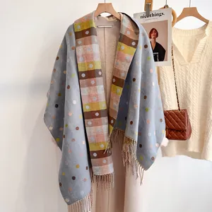 Close-up of light blue polka dot scarf with cashmere texture and colorful plaid fringe details