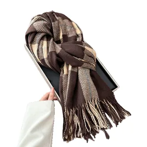 Plaid warm scarf in brown and beige with tassels held against a white backdrop