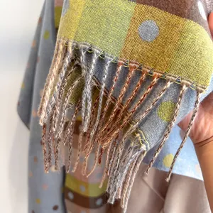 Close-up of soft colorful polka dot scarf with detailed long fringe and woven texture