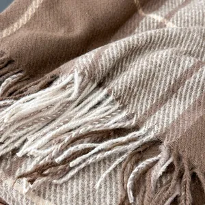 Close-up of classic brown and beige plaid scarf showing soft twill weave and fringe detail