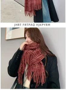 Close-up of a burgundy plaid scarf with fringe and soft woven texture on a model