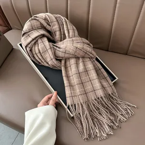 Classic brown plaid cashmere scarf with long tassels displayed on a leather background
