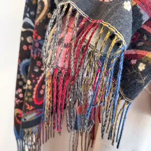 Detailed view of colorful paisley patterns and handmade tassel fringe on a black scarf