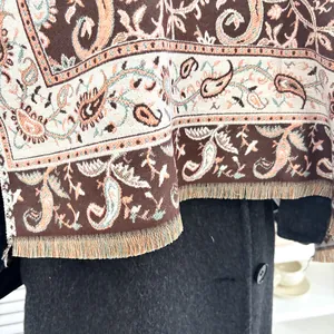 Detailopname van de bruine paisley jacquard sjaal met decoratieve franjeranden