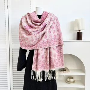 Close-up of pink paisley cashmere scarf with delicate tassels on a black coat