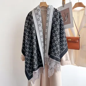 Détail d'une écharpe jacquard réversible avec franges et motif sur un manteau blanc