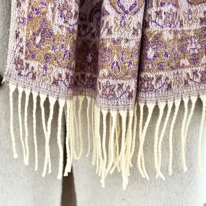 Detailed view of paisley patterns and cream-colored tassels on a warm scarf