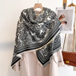 Close-up of black and white Toile de Jouy scarf with delicate fringe on wool coat