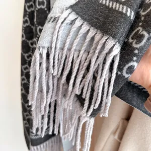 Gros plan détaillé de l'écharpe avec texture en maille, motif jacquard GG et franges