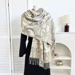 Detailed view of beige paisley jacquard shawl with tassel fringe on a mannequin