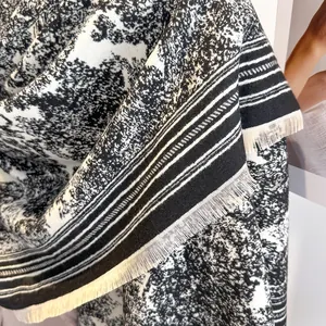 Close-up of black and white Toile de Jouy pattern shawl with delicate cream fringe