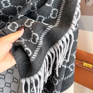 Vue détaillée d'une écharpe épaisse de luxe avec motif monogramme gris et noir et franges