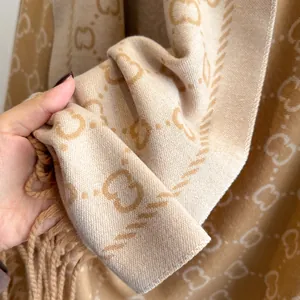 Gros plan de l'écharpe en maille jacquard épaisse avec motifs de lettres et franges fines