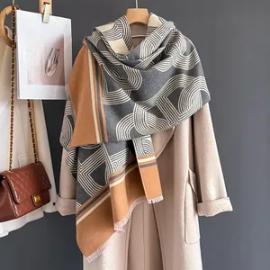 Dettaglio di una spessa sciarpa invernale con motivi geometrici e frange su un cappotto