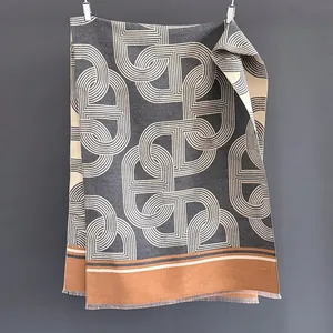 Dettaglio della sciarpa grigio scuro con motivo a catena beige e frange arancioni