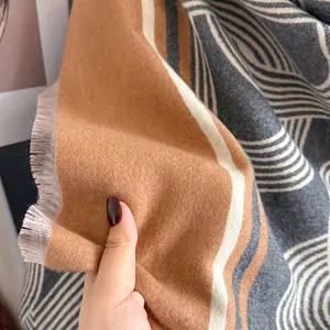 Dettaglio di una sciarpa morbida effetto cashmere con motivi geometrici e frange