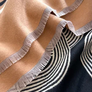 Dettaglio di morbida sciarpa effetto cashmere con elegante tonalità cammello e frange
