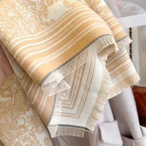 Close-up of floral jacquard knit scarf with refined fringe and soft cream stripes