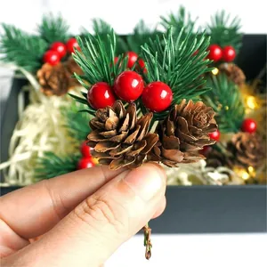Weihnachtszweig mit roten Beeren und Tannenzapfen in einer leuchtenden Geschenkbox