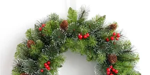 Close-up of Christmas wreath with frosted pine needles, red berries and pine cones