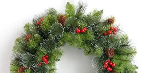 Close-up of Christmas wreath with pine needles, red berries and snow-dusted cones