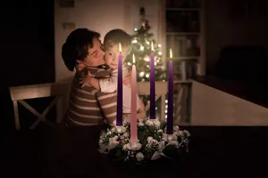 Atmosfera natalizia con quattro candele dell'Avvento accese e famiglia in festa