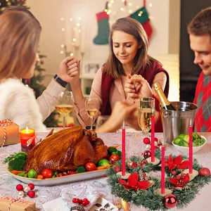 Famiglia in preghiera a cena di Natale con ghirlanda festiva e candele rosse