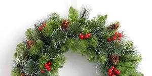 Close-up of frosted green pine needles, red berries and brown pinecones on a Christmas wreath