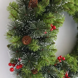 Close-up of Christmas wreath featuring green pine needles with snow and red berries