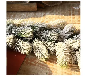 Macro detail of artificial Christmas garland with realistic snow frost on green pine needles