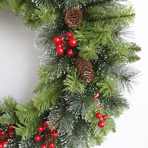 Detail of pine needles with red berries and snow-dusted pine cones for Christmas wreath