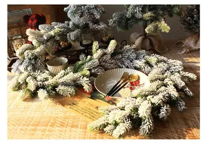 Detail view of snow-flocked faux pine garland on a rustic wooden table for Christmas decor