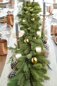 Close-up of lush PE Christmas garland with golden ornaments and natural pine cones