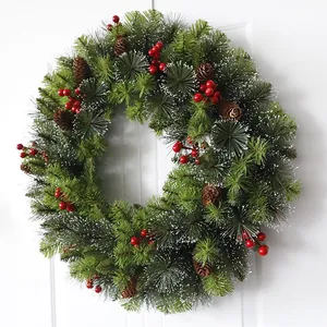 Christmas wreath with artificial pine needles, pine cones and red berries on white door