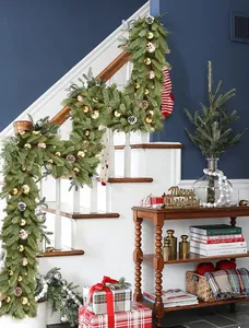 Christmas garland with pine cones and metallic ornaments on a white staircase railing