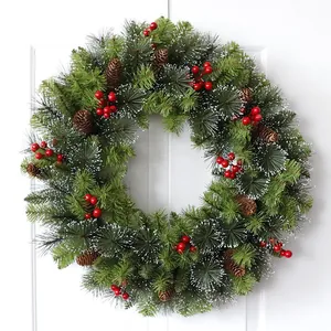Christmas wreath with pine needles, cones and red berries on a white wooden door