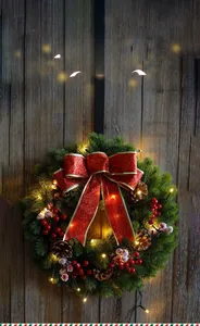 Macro detail of 40cm PE Christmas wreath with LED lights, red bow and pine cones on wood