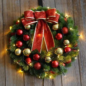 Green PE Christmas wreath with LED lights, red bows, and gold baubles on wood background