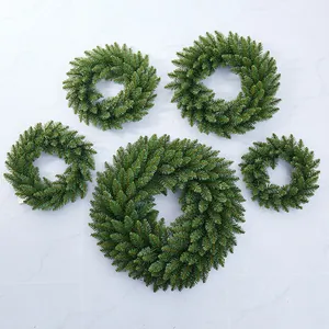 Five assorted sizes of artificial green PVC Christmas wreaths on gray marble background