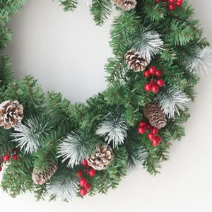 Christmas wreath with green pine needles, natural pine cones and red berries on white background