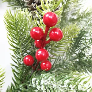 Macro detail of red berries with fake snow on green pine needles and a pine cone
