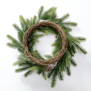 Close-up of PE pine needles with snowy cones and red berries on a Christmas wreath