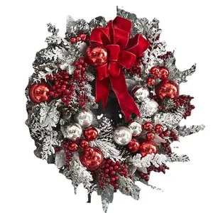 Classic Christmas flocking wreath with red velvet bow, silver ornaments and snowy pine branches