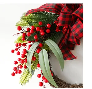 Detail of Christmas wreath with red berries, pine cones, and buffalo plaid bow decoration